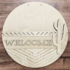 a wooden sign that says welcome with a cactus in the center on a wood background