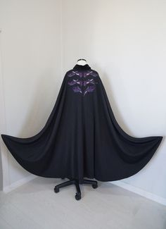 a black cape sitting on top of a wooden table next to a white wall in a room