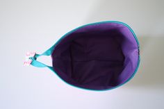 an empty purple and blue purse on a white surface