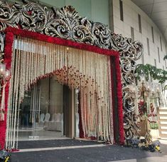 the entrance to a wedding venue decorated with red and white flowers, beads and chains