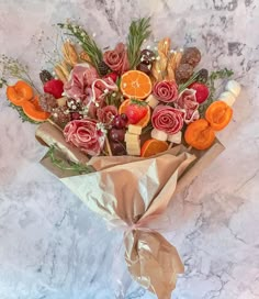 a bouquet of fruit and flowers wrapped in brown paper on a marble countertop,