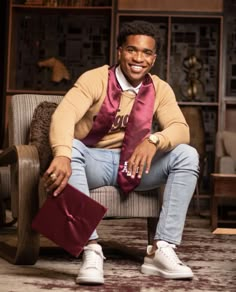 a man sitting on top of a couch wearing a tie and holding a book in his lap