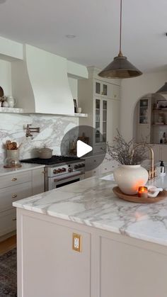 a kitchen with marble counter tops and white cabinets in the background, an island has a bowl on it