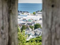 the view from behind a wooden fence looking down at houses and water in the distance