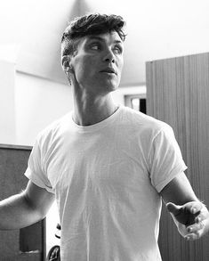 black and white photograph of a man holding a wii remote in his hand while looking up at the ceiling