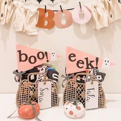 two baskets with halloween decorations on them sitting in front of a sign that says boo eek