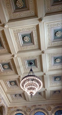 a chandelier hanging from the ceiling in a room with ornate ceilings and windows