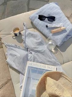 a hat, sunglasses and other items are laid out on a blanket next to a cup of coffee