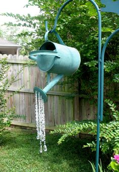 a blue watering can with chains hanging from it's side next to a fence