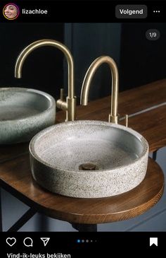 two bathroom sinks sitting next to each other on a wooden table with metal faucets