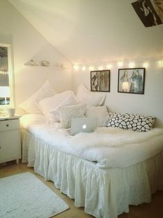 a white bed sitting in a bedroom next to a wall with pictures hanging on it