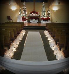 a church decorated for christmas with candles and flowers on the pews in front of it