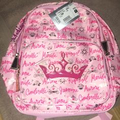 a pink backpack with a crown on it and name tags attached to the front pocket