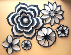 paper flowers are arranged on the wall with black and white petals, one large flower is surrounded by smaller ones