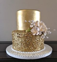 a gold and white cake with flowers on top