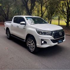 a white truck is parked on the side of the road in front of some trees