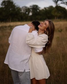 a man and woman hugging in the middle of a field