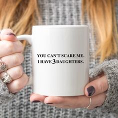 a woman holding a coffee mug with the words you can't scare me i have daughters