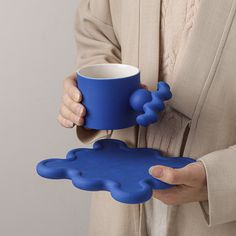 a person holding a blue mug in one hand and an object in the other with two hands