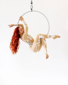 a woman with red hair is doing aerial acrobatics on a hoop swing