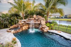 a pool with a waterfall and some palm trees in the backround, surrounded by water features