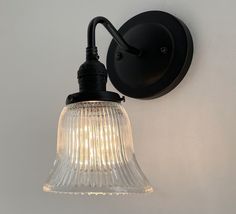 a light that is on the side of a wall next to a white wall with a glass shade