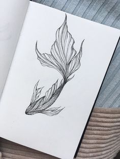 an open book with a drawing of a feather on it