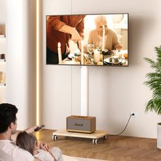 a man and woman sitting on a couch watching tv with their child in front of them