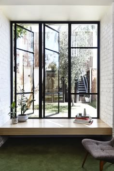 an open window in a white brick wall with books and plants on the table next to it