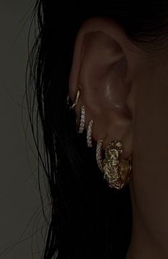 a close up of a person wearing gold ear rings and earrings with diamonds on them