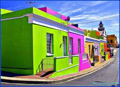 a colorful building on the corner of a street with buildings painted in different colors and shapes