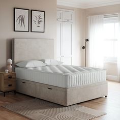 a white bed sitting on top of a wooden floor next to a dresser and window