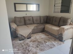 a living room with a sectional couch and rugs on the floor in front of it