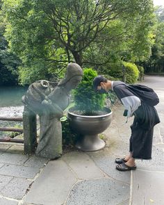 a woman standing next to a statue near a pond