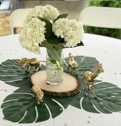 a vase filled with white flowers sitting on top of a wooden table next to figurines