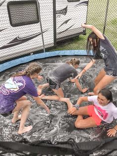 four girls are playing in the water on a trampoline