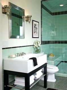 a bathroom with green tiles and a white toilet next to a walk - in shower