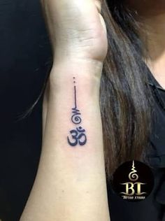 a woman's wrist tattoo with an omen symbol on it