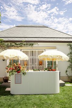 an outdoor bar with two umbrellas over it and flowers on the table in front