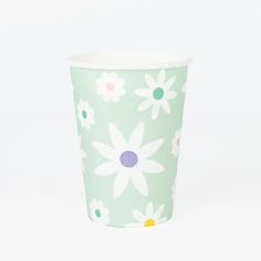 a paper cup with flowers painted on the side and dots in the middle, sitting against a white background