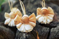 three wooden angel ornaments sitting on top of a tree stump