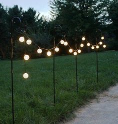 a row of lights sitting on top of a lush green field next to a sidewalk