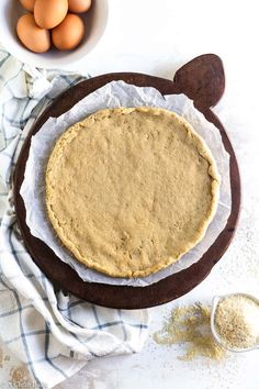 an uncooked pie sitting on top of a table next to eggs and flour