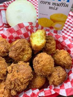 a basket filled with fried food next to a box of cornmeal muffins