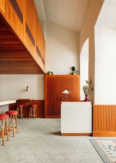 an empty room with stools and bar in the center, next to wooden paneled walls