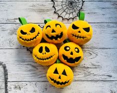 pumpkins with faces carved into them sitting on a wooden surface next to a spider web