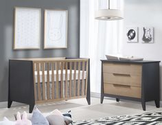 a baby crib in a room with two pictures on the wall and a rug