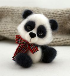 a small stuffed panda bear with a red bow