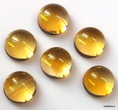 six yellow glass buttons on a white surface