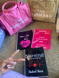 a person sitting on the floor next to three books and a bag with writing on them